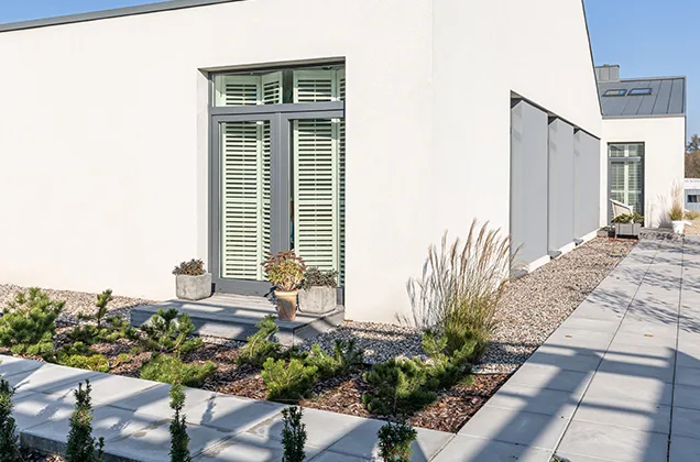 Elevate-Your-Outdoor-Living-Experience A man in work attire installing pavers on a prepared outdoor surface. He is using tools to carefully position and arrange the pavers, showcasing the meticulous process of paver installation for a driveway or patio project.